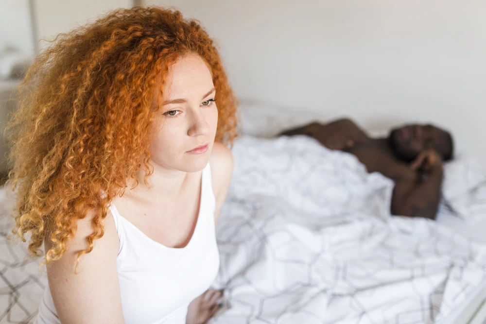 femme triste au lit avec son conjoint